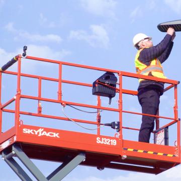 Worker fixing a street light standing atop the SJ3219